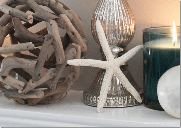 Home decorating ideas and tips: Learn how to decorate a Summer Beach Inspired Mantel with coastal colors and beach style accessories! Add pretty summer decor to your living room mantel with aqua blue candles, starfish, driftwood and capiz shell accents and a statement mirror.
