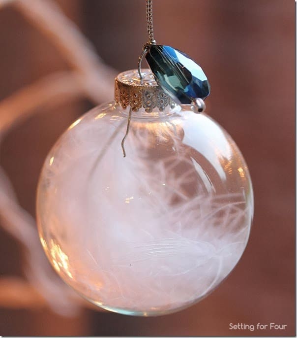 Clear glass ornament filled with feathers and topped with a jewel accent - see the tutorial to make this gorgeous DIY Christmas ball ornament!