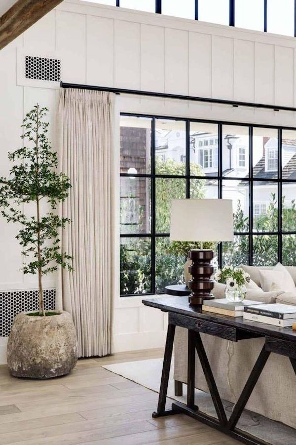 Elegant Neutral Living Room Decor Ideas. cozy living room decor, classy, minimalist, modern, farmhouse, simple, olive tree, wood floors, living room area rug, black console table decor ideas, black windows, black curtain rod and neutral color curtains, color scheme, color palette ideas, 