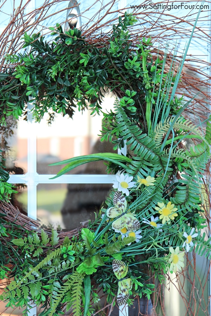 So pretty! Make thisDIY boxwood wreath with ferns and butterflies to add some cheer to your front door! www.settingforfour.com