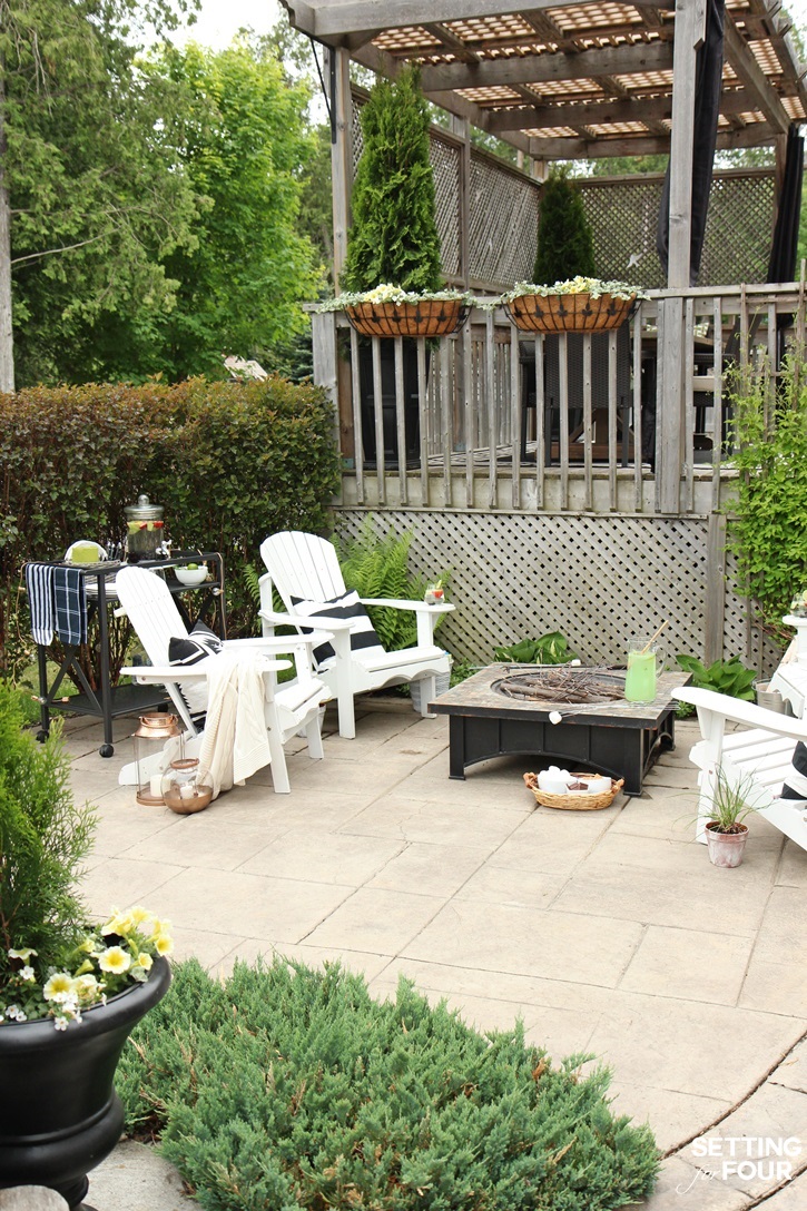 See this beautiful summer FIRE PIT SEATING AREA with white adirondack chairs and a bar cart for entertaining.