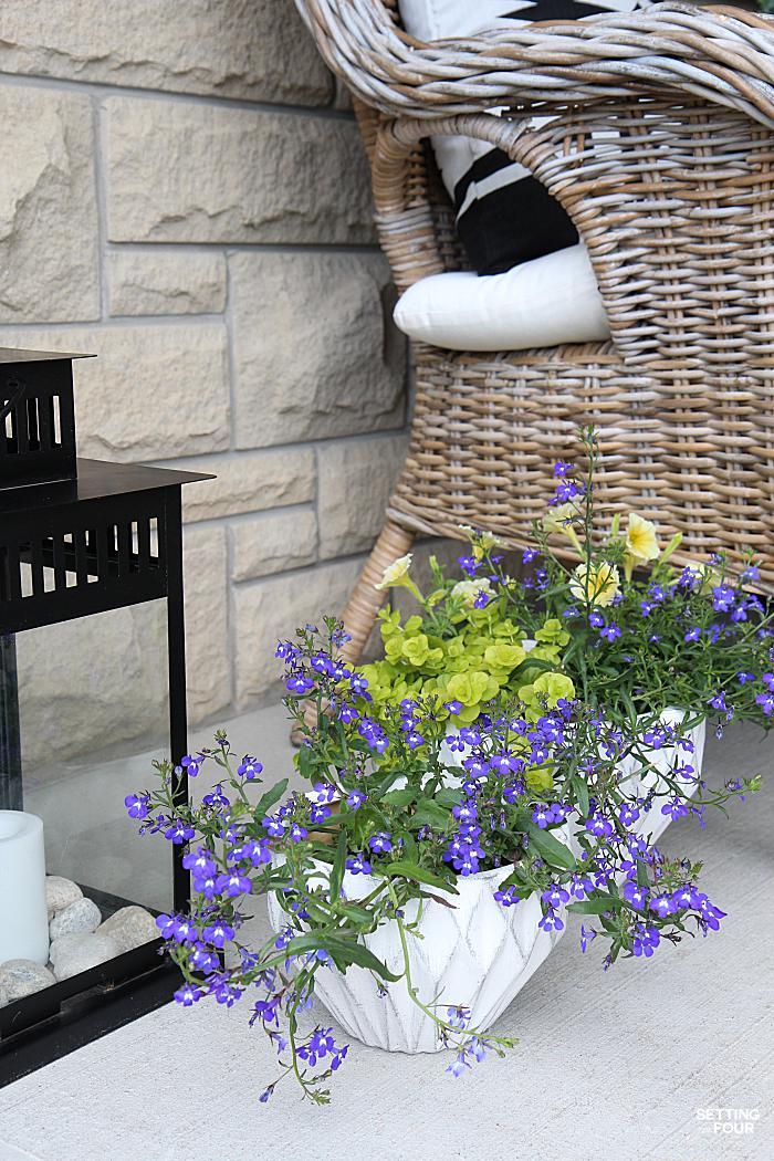 Summer home tour and summer decorating ideas. Wicker chairs, blue colored lobelia planters and outdoor lanterns.