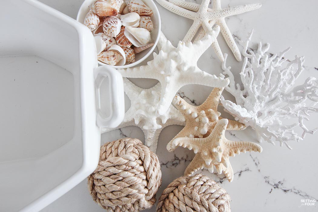 Learn how to make a Pretty Faux Coral & Starfish Coastal Summer Centerpiece that's quick and easy to put together! This Pottery Barn inspired centerpiece is the perfect table top, coffee table and bookshelf decor to update your home for summer and for fun events like parties and weddings. If you love coastal decor and collect shells you'll love this beautiful sea inspired arrangement!