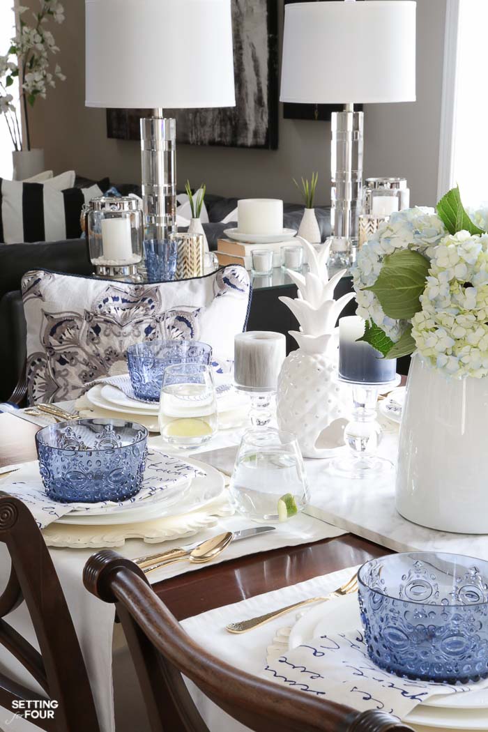 Blue and white napkins, blue bowls, white ceramic pineapple decor, blue hydrangea centerpiece layered together for a summer tablescape.