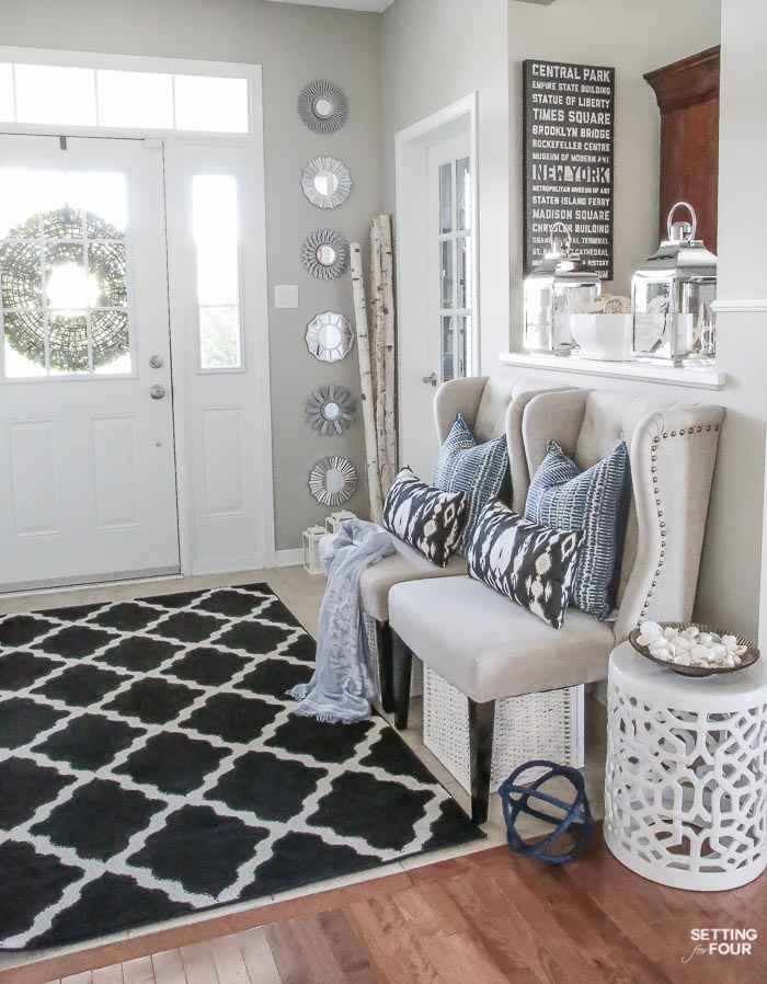 Need some new decorating ideas? See my foyer decor ideas including my indigo blue, black and gray color scheme, make this DIY coastal centerpiece, lanterns, garden stool, seating, area rug and pillow accents.