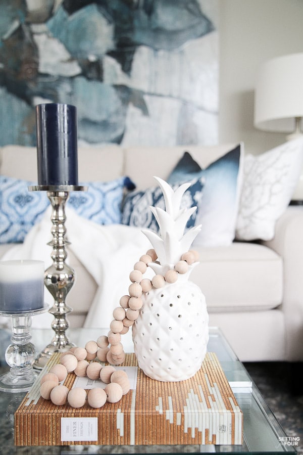 Summer decor ideas and design blogger's home tour. Indigo black and gray color scheme. Abstract art, indigo pillows, cream sofa, white pineapple, prayer bead garland and coffee table vignette.