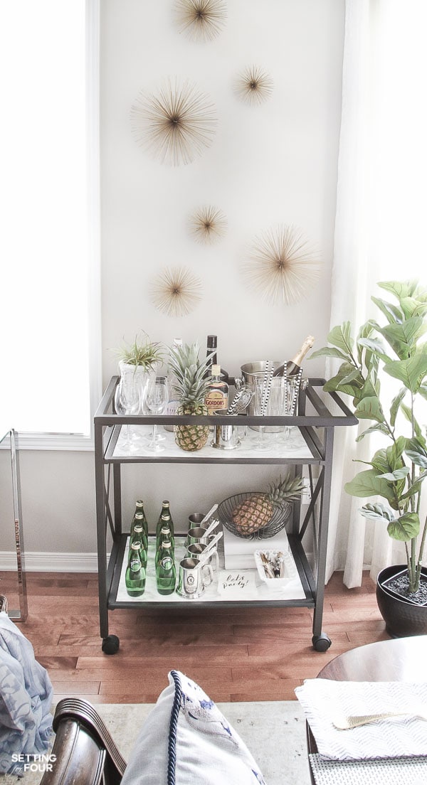 Bar cart decorated with marble shelves, barware, cocktail drinks, and wall art idea.