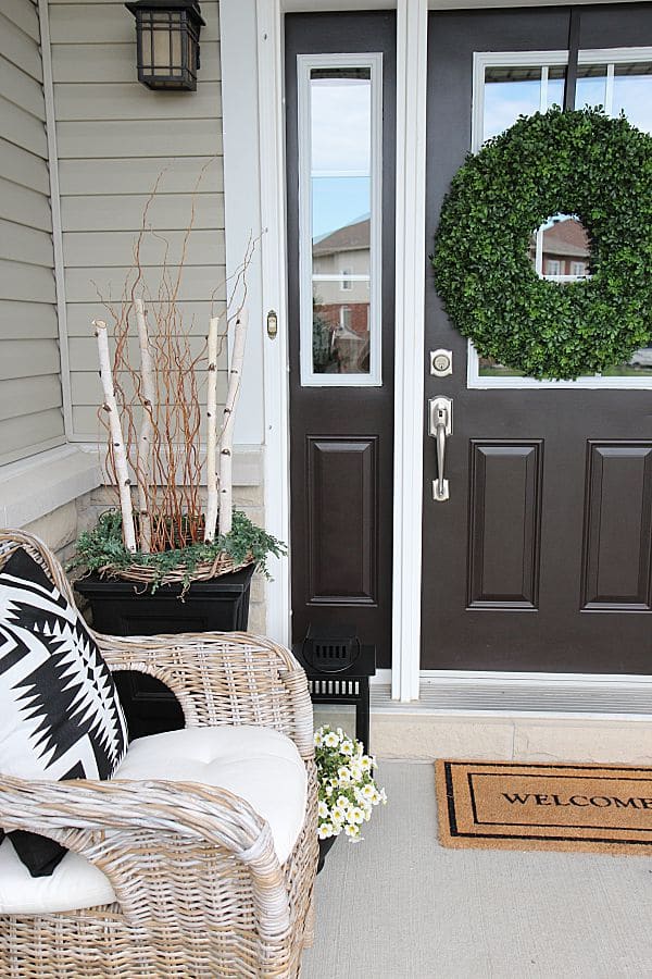 Summer home tour and summer decorating ideas. Front door wreath, urn planters with birch, wicker chairs, blue colored plants.