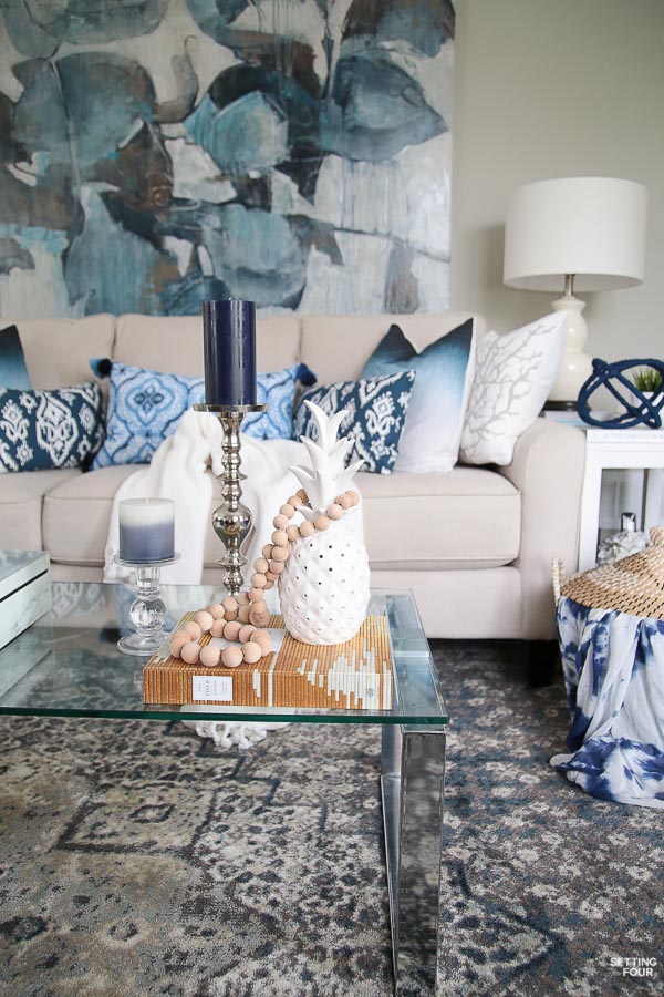 Summer decor ideas and design blogger's home tour. Indigo black and gray color scheme. Abstract art, indigo pillows, cream sofa, white pineapple, prayer bead garland and coffee table vignette.