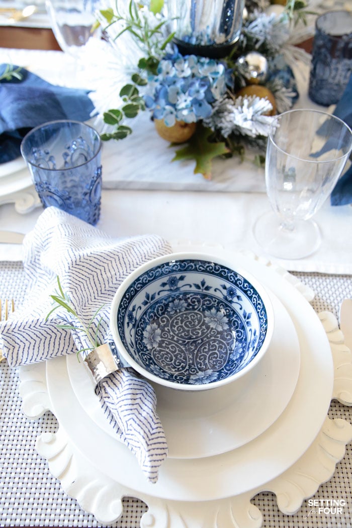 Learn how to create these elegant fall table settings with a blue and white color palette using white dishes, blue and white chinoiserie bowls, navy napkins, sparkly mercury glass and a transitional holiday centerpiece accented with fall herbs, garden greenery and orchard pears.