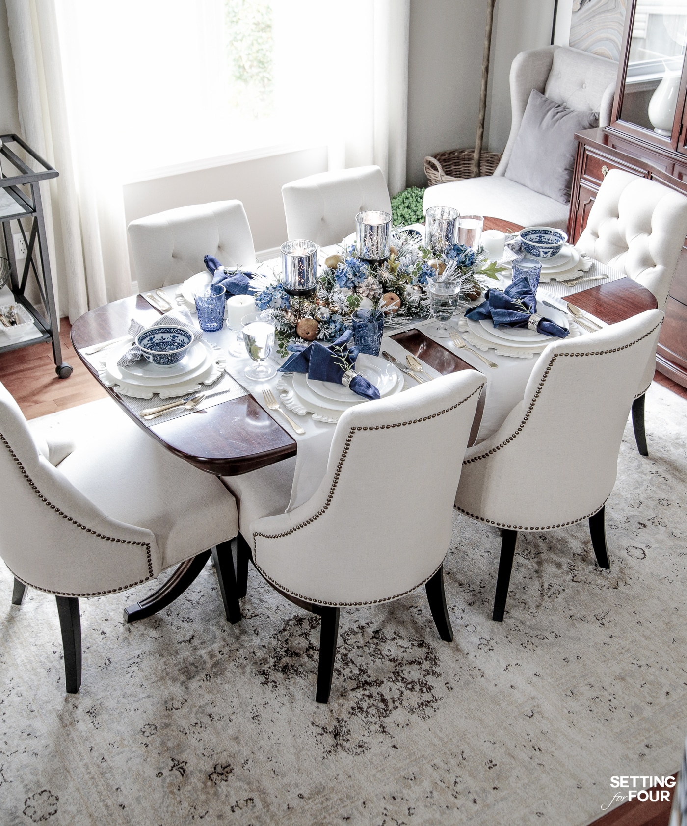 Learn how to create these elegant fall table settings with a blue and white color palette using white dishes, blue and white chinoiserie bowls, navy napkins, sparkly mercury glass and a transitional holiday centerpiece accented with fall herbs, garden greenery and orchard pears.