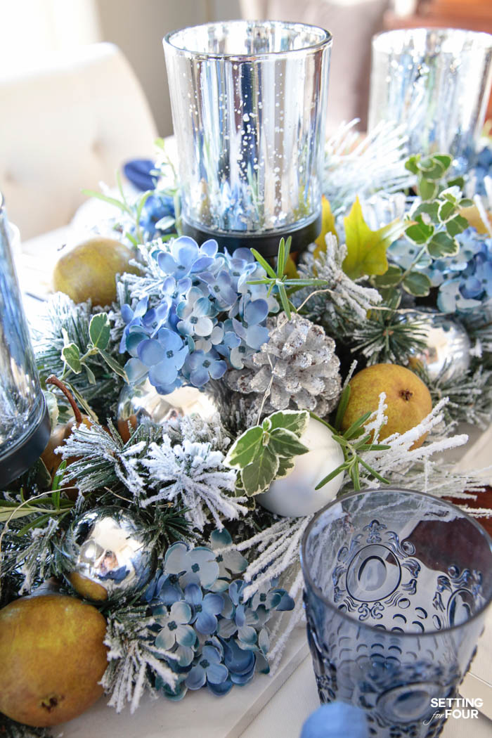 Learn how to create these elegant fall table settings with a blue and white color palette using white dishes, blue and white chinoiserie bowls, navy napkins, sparkly mercury glass and a transitional holiday centerpiece accented with fall herbs, garden greenery and orchard pears.