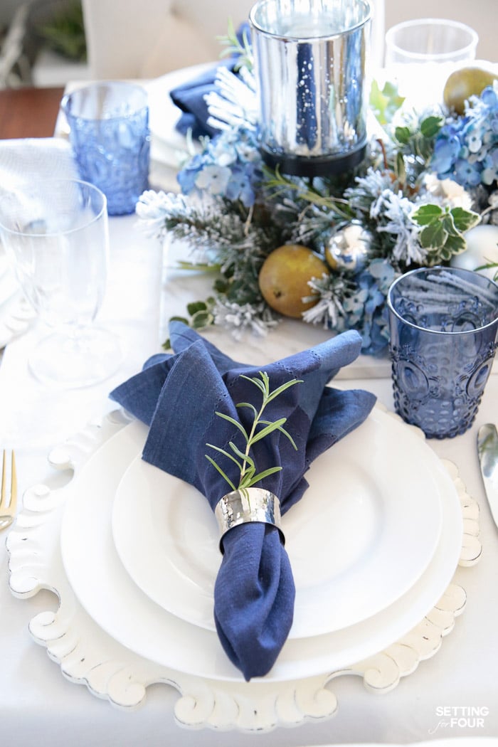 Learn how to create these elegant fall table settings with a blue and white color palette using white dishes, blue and white chinoiserie bowls, navy napkins, sparkly mercury glass and a transitional holiday centerpiece accented with fall herbs, garden greenery and orchard pears.