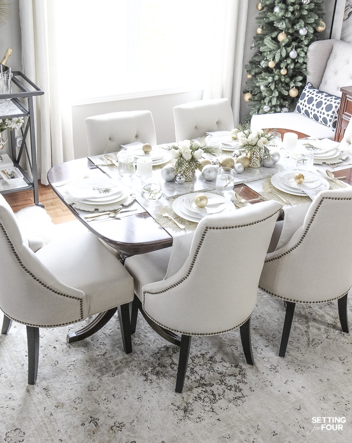 Learn how to create this Elegant Gold And White Christmas Tablescape that's quick and easy to put together! Give white dishes a festive look with white, silver and gold Christmas ball ornaments and beautiful DIY white rose and pine winter centerpieces. This Christmas table decor is perfect for holiday dinner with the family, big dinner parties and winter weddings too!