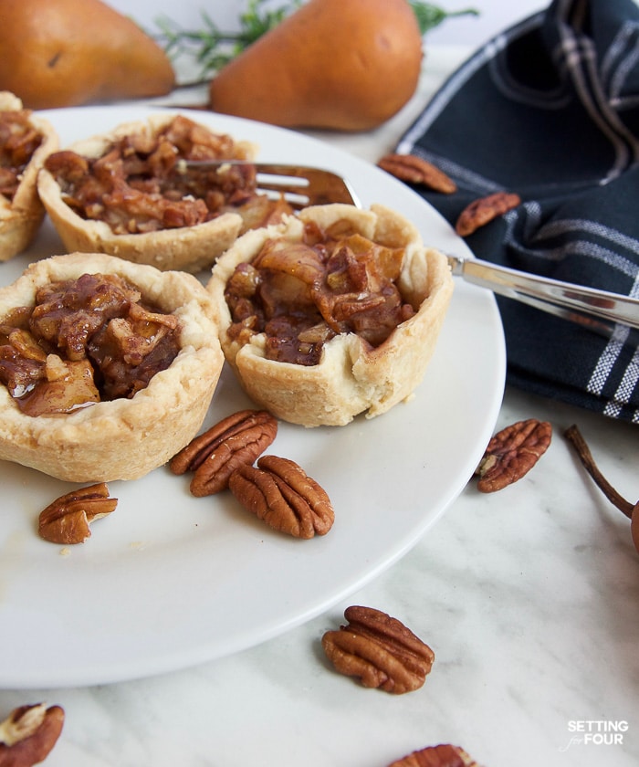 Make this quick and easy Cinnamon Pecan Pear Tartlets recipe with delicious maple syrup, ready to bake in just 20 minutes! Add yummy maple cream to these miniature pies as a topping. NO handmade pie crust required: This recipe turns store bought pie crust into these beautiful ruffled tartlets for easy baking!