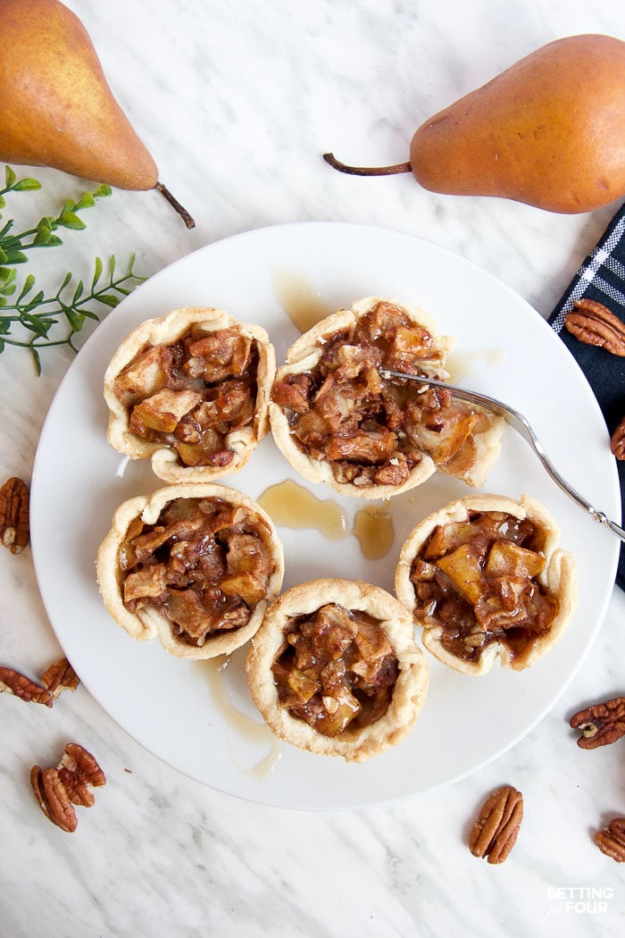 Make this quick and easy Cinnamon Pecan Pear Tartlets recipe with delicious maple syrup, ready to bake in just 20 minutes! Add yummy maple cream to these miniature pies as a topping. NO handmade pie crust required: This recipe turns store bought pie crust into these beautiful ruffled tartlets for easy baking!