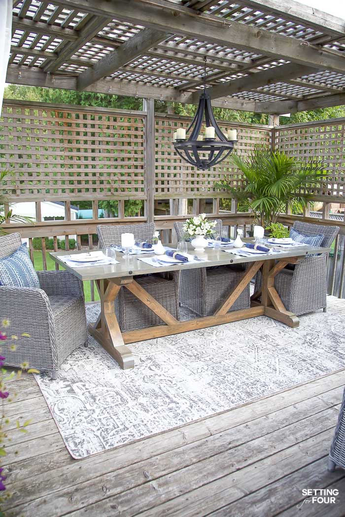 Outdoor pergola dining area with wood trestle table and wicker chairs