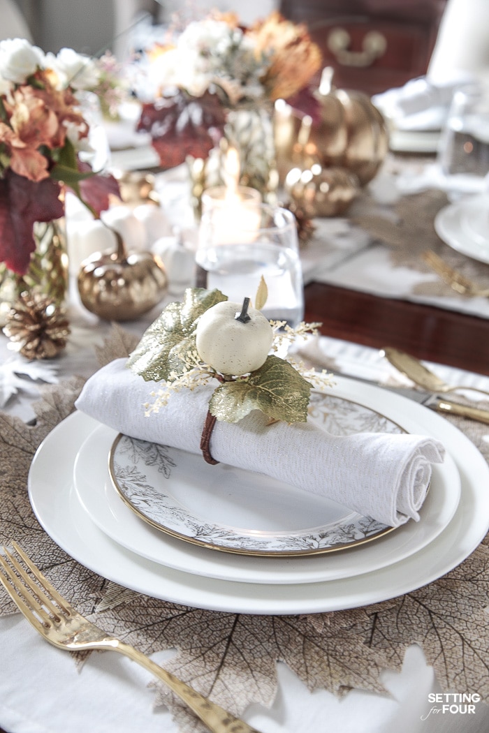 An elegant gold and white Thanksgiving tablescape. Table decorating tips and place setting ideas. #thanksgiving #entertaining #tabletop #napkinfold #pumpkin #decoration #holiday #dinnerparty