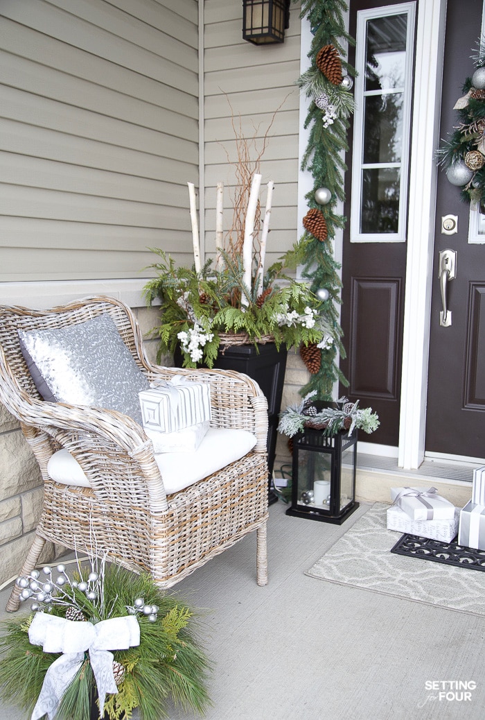 Christmas porch with seating, winter planters, lanterns and garland. #decorideas #exteriordesign #design #interiordecorator