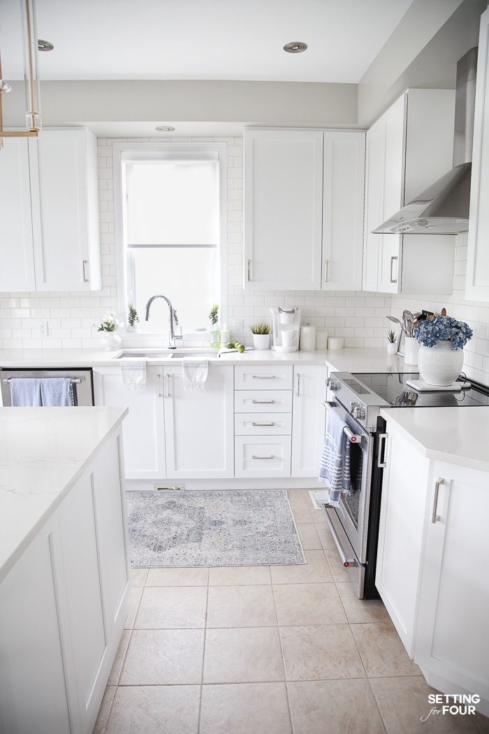 Kitchen with white cabinets, blue rug in front of sink and blue tea towels.