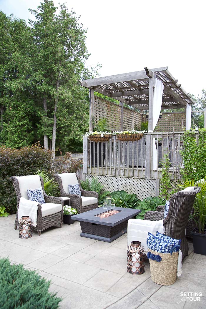 Backyard patio seating area with fire table and hosta plants in a landscaped backyard.