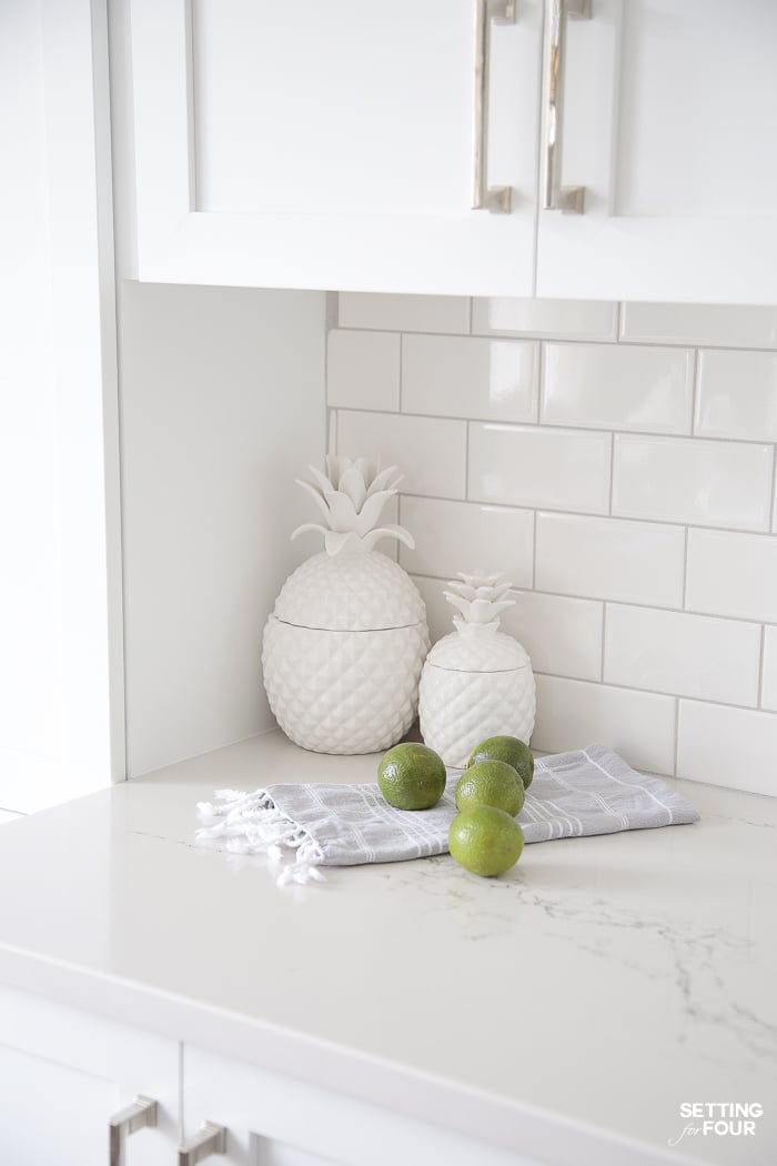 White ceramic pineapple canisters on a kitchen countertop for storage.