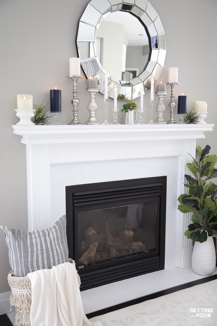 White fireplace with mirror, candlesticks, basket and vase of greenery!