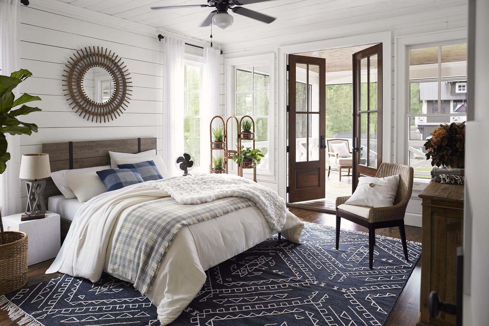 Blue and white lake house bedroom with blue rug and shiplap walls.