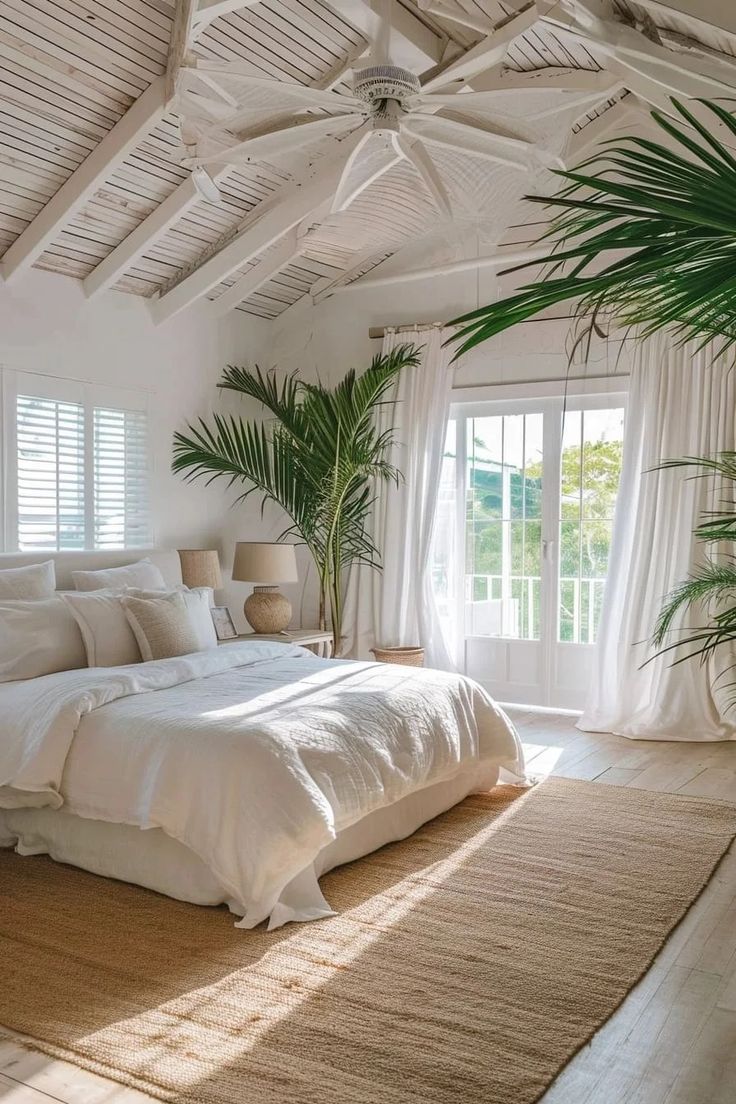 Modern Coastal Bedroom Decor Ideas. blend of traditional and modern, palm tree decor, white ceiling fan, jute rug, french doors, bedroom balcony, tropical, beach house, airbnb ideas