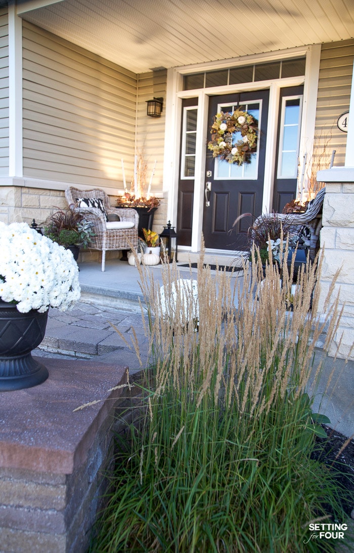 Porch with lighting decorated for fall with a fall wreath and mums.