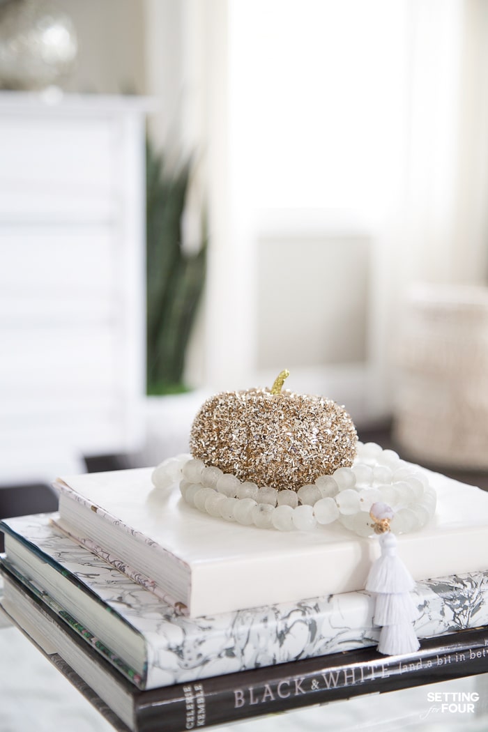 Elegant Fall Living Room Decor Ideas. Decorated coffee table for fall with gold tinsel pumpkin on a stack of coffee table books.