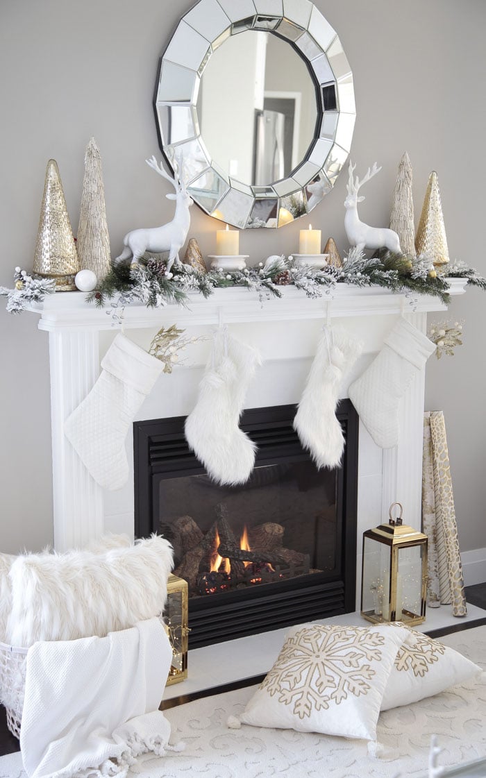 Christmas mantel decor with reindeer, garland and glass Christmas trees.