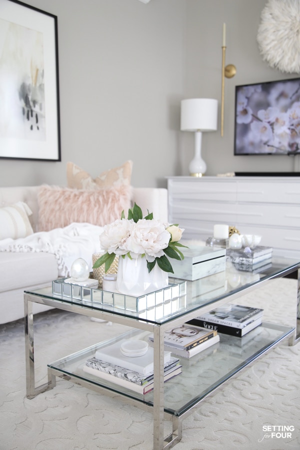 Glam modern glass coffee table with decor in bright living room with gray walls