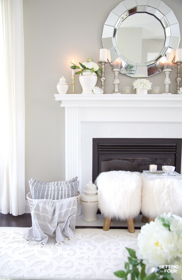 Fireplace mantle decorated for summer with white ginger jars, candles, mirror