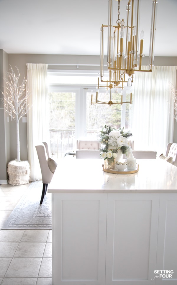 Pre-lit birch trees in baskets in a white kitchen. Holiday decor ideas