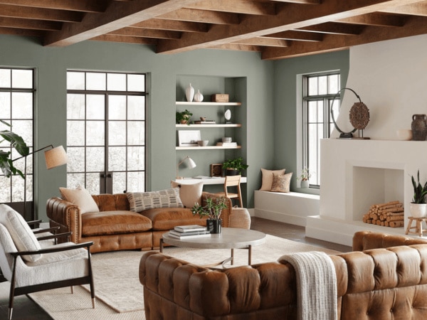 Sherwin Williams Evergreen Fog living room paint color idea. Wood ceiling beams. Fireplace. Leather furniture.