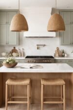 Sherwin Williams Evergreen Fog Kitchen Cabinets Paint Color Idea, green kitchen cabinets with quartz countertops, brushed brass hardware, brushed brass pot filler over range, floating wood shelves, woven pendant lights over the kitchen island, white oak island and light wood floors, and two kitchen island stools, cozy, calm, tranquil kitchen decor ideas, interior design ideas for the kitchen, painted cabinetry inspiration, earthy, moody, neutral aesthetic, modern, transitional, minimalist home ideas, new home inspo, kitchen layout ideas and island size for 2 counter stools, bright, elegant