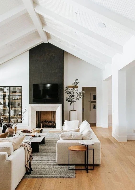 Cozy Modern Living Room Design and Decor Ideas, large great room with vaulted ceiling with shiplap and beams, black fireplace with modern fireplace surround, minimalist aesthetic, organic modern, transitional, white walls, 2 sofas furniture arrangement, long living room that is open concept, neutral color palette, black windows, new home ideas, black and white color scheme, 2026 trends, Nancy Meyers style