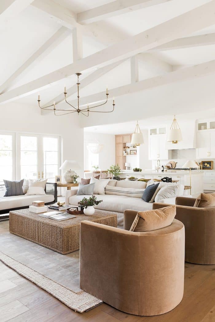 Cozy living room decor ideas with beams, white walls and neutral furniture. Furniture layout with 2 sofas and 2 chairs. brass pendant. open concept. organic modern. transitional. interior design ideas