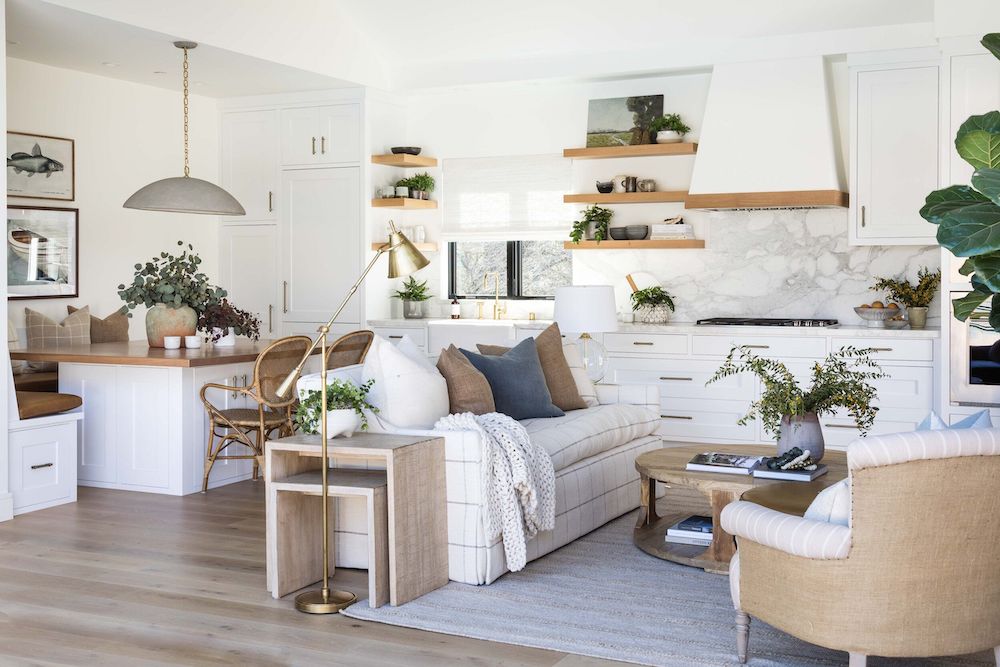 Small Open Concept Layout With Living Room, Kitchen and Banquette Dining Nook, eat in kitchen open floor plan design ideas, white kitchen cabinets with white walls, floating wood shelves, shelf decor ideas, gray cement pendant over dining table, banquette table repurposed as kitchen island, slab backsplash, 2026 trend, interior design, cozy, modern, minimalist, farmhouse, organic, neutral color palette