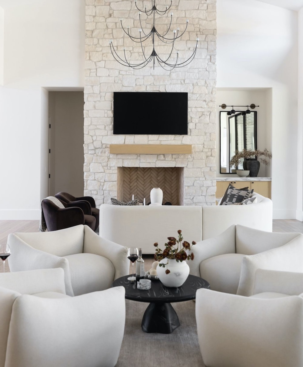 Open Floor Plan Furniture Layout Ideas With 4 Chairs Seating Area separate from the living room seating zone with sectional sofa and 2 chairs across from natural stone fireplace, black living room chandelier, builtin cabinets, TV above fireplace, white, black, brown, bright, light, modern, transitional, minimalist, new home ideas, round coffee table decorating inspiration