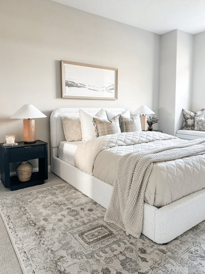 Organic Modern Bedroom Decor and Design Idea, sherwin williams repose gray paint color on walls, upholstered bed, black nightstands, landscape art above bed, layered rug over carpeting, neutral color palette, cozy, transitional interior
