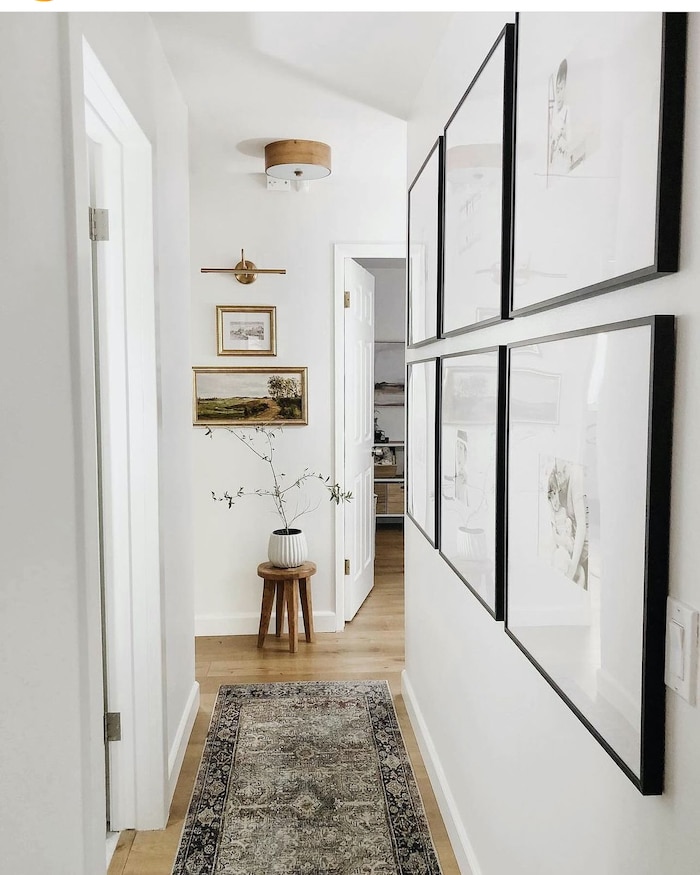 Beautiful neutral hallway decor ideas. Gallery Wall of family photos, vintage landscape art, runner rug, white walls, organic modern, farmhouse, transitional design ideas.