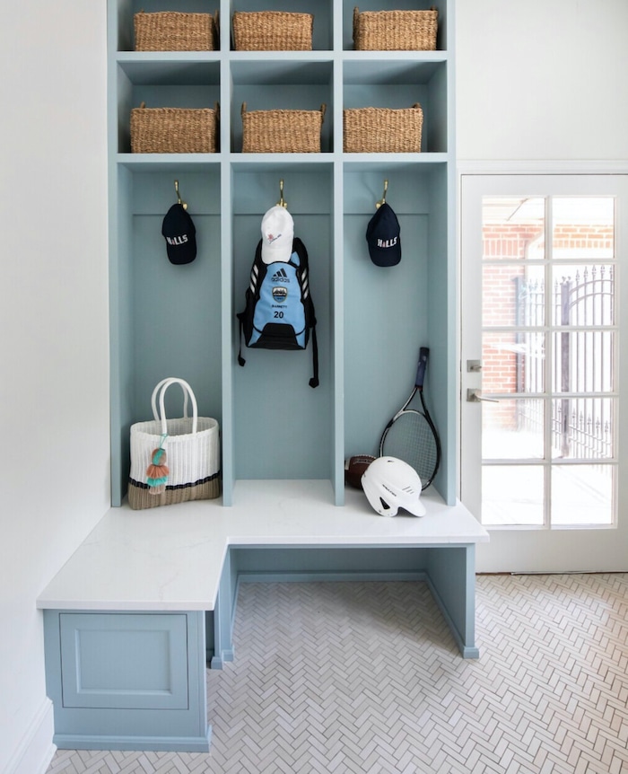 Beautiful Mudroom Built In Ideas To Store Backpacks and Outwear. L shaped bench. Open cubbies, wall hooks with open bottom mudroom bench. Elegant blue paint color creates a coastal design style.