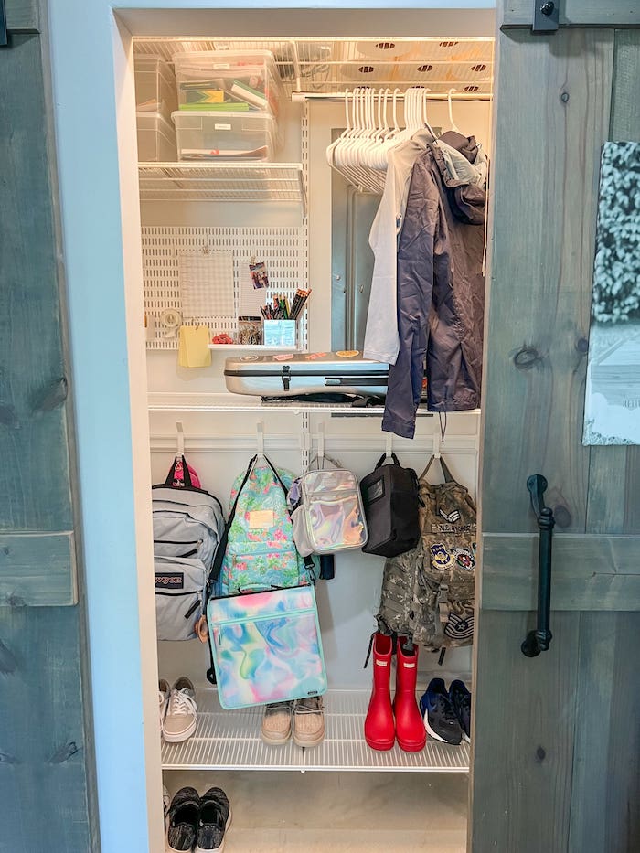 Backpack storage  and organization ideas for a closet - organized shelves and hanging space. How to remove closet clutter and create a tidy closet with wire shelving units and hooks. Barn doors optimize a small entryway. 