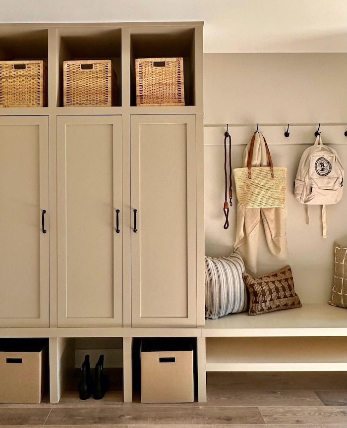Neutral beige built in cabinets for a mudroom. Mudroom bench with shoe storage and backpack organization, hooks for dog leashes and cozy pillows.