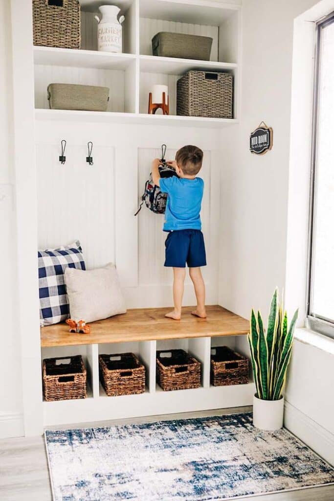 Bright, Organized Mudroom Decor and Design Ideas.  Mudroom built in bench. White and wood builtins with wall hooks for backpack storage, cubbies for shoes and baskets to store and organize kids stuff.