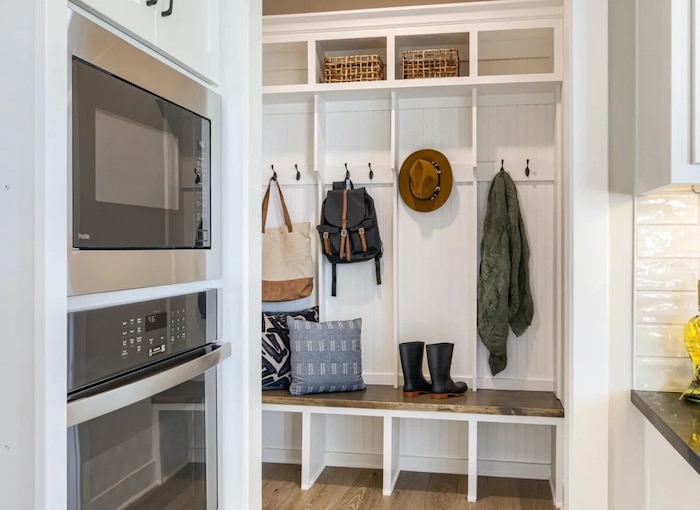 Mudroom bench with storage and hooks to store backpacks, coats, purses, hats. Cubbies under the bench for shoe storage.