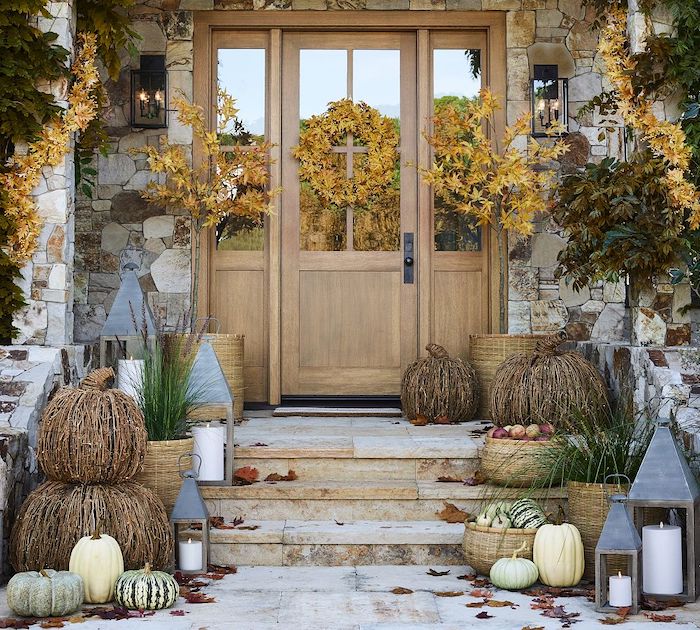 Neutral Front porch with autumn decor, featuring wicker pumpkins, white and green gourds, lanterns, and baskets of apples. Warm tones create a cozy, festive mood. Neutral Front Porch Decor Ideas For Fall, Thanksgiving and Halloween.