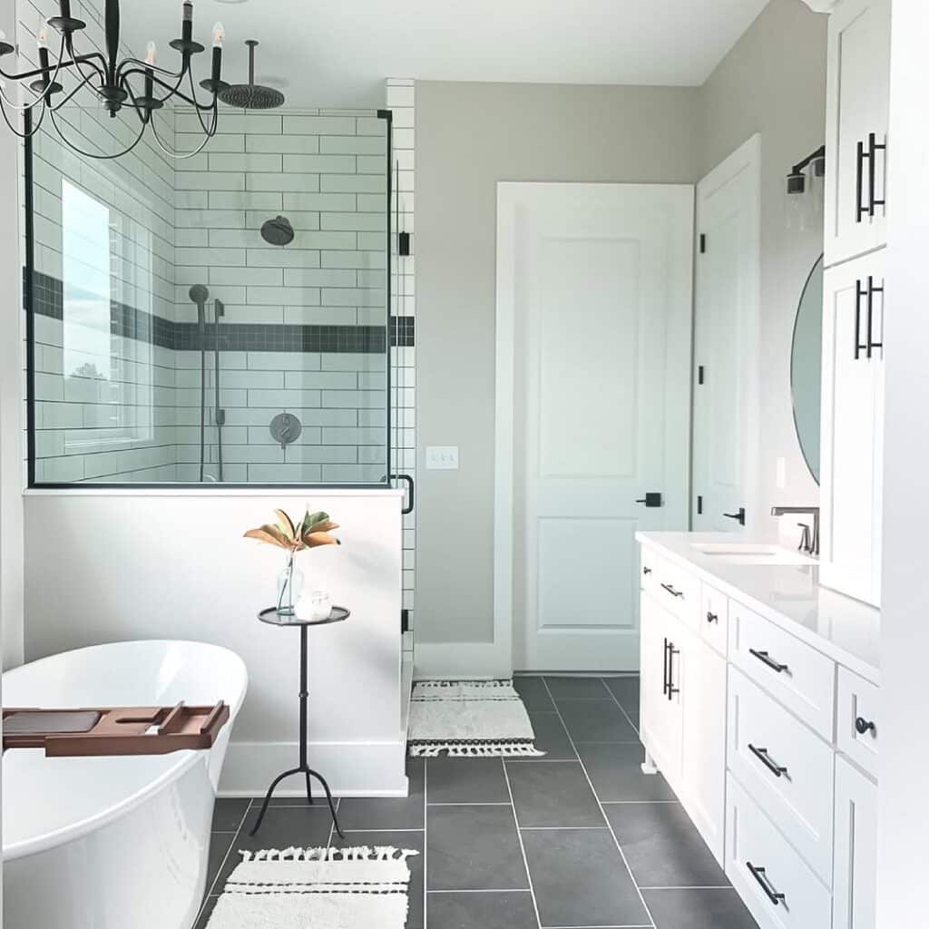 Sherwin-Williams Repose Gray bathroom walls with white cabinetry, black hardware, white subway tile shower, dark floor tile, and glass shower enclosure
